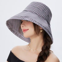 Woman wearing a checkered sun hat on a white background