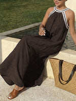Woman in a brown dress sitting by a fountain with a straw bag next to her.