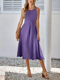 Woman wearing a purple dress standing outdoors with a neutral background
