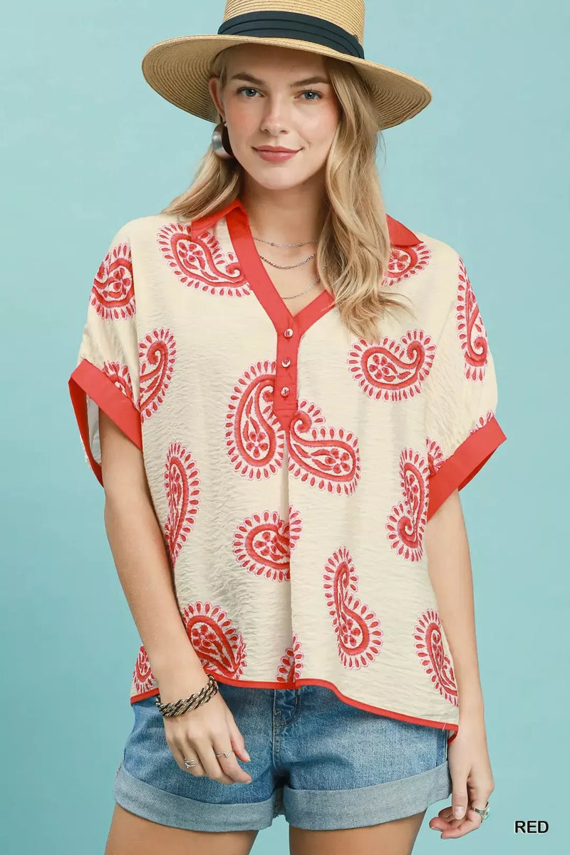 Woman wearing a patterned top and shorts with a straw hat against a light blue background