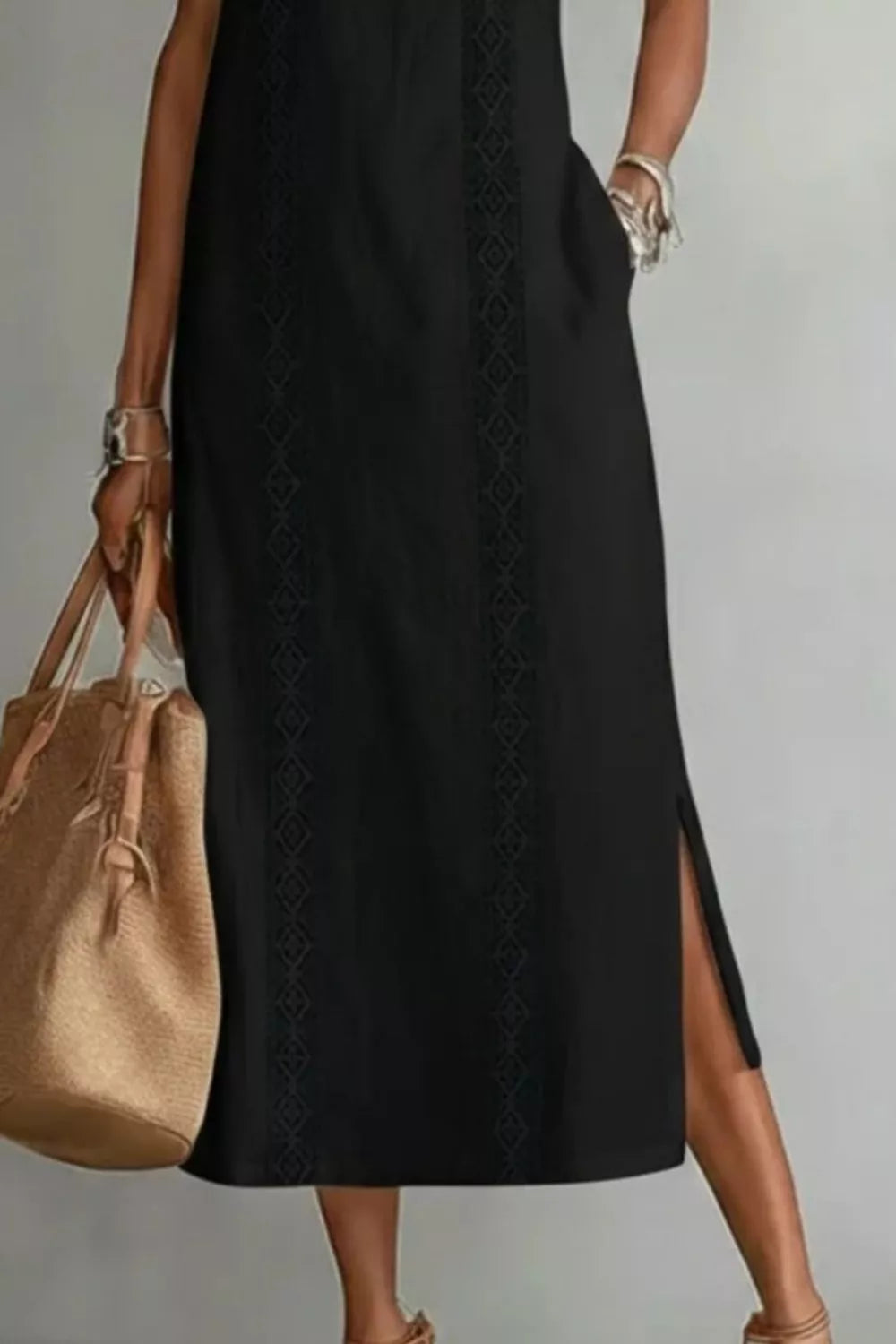 Woman wearing a black dress with a beige handbag on a plain background