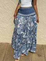Person wearing a blue and white patterned skirt against a beige wall.