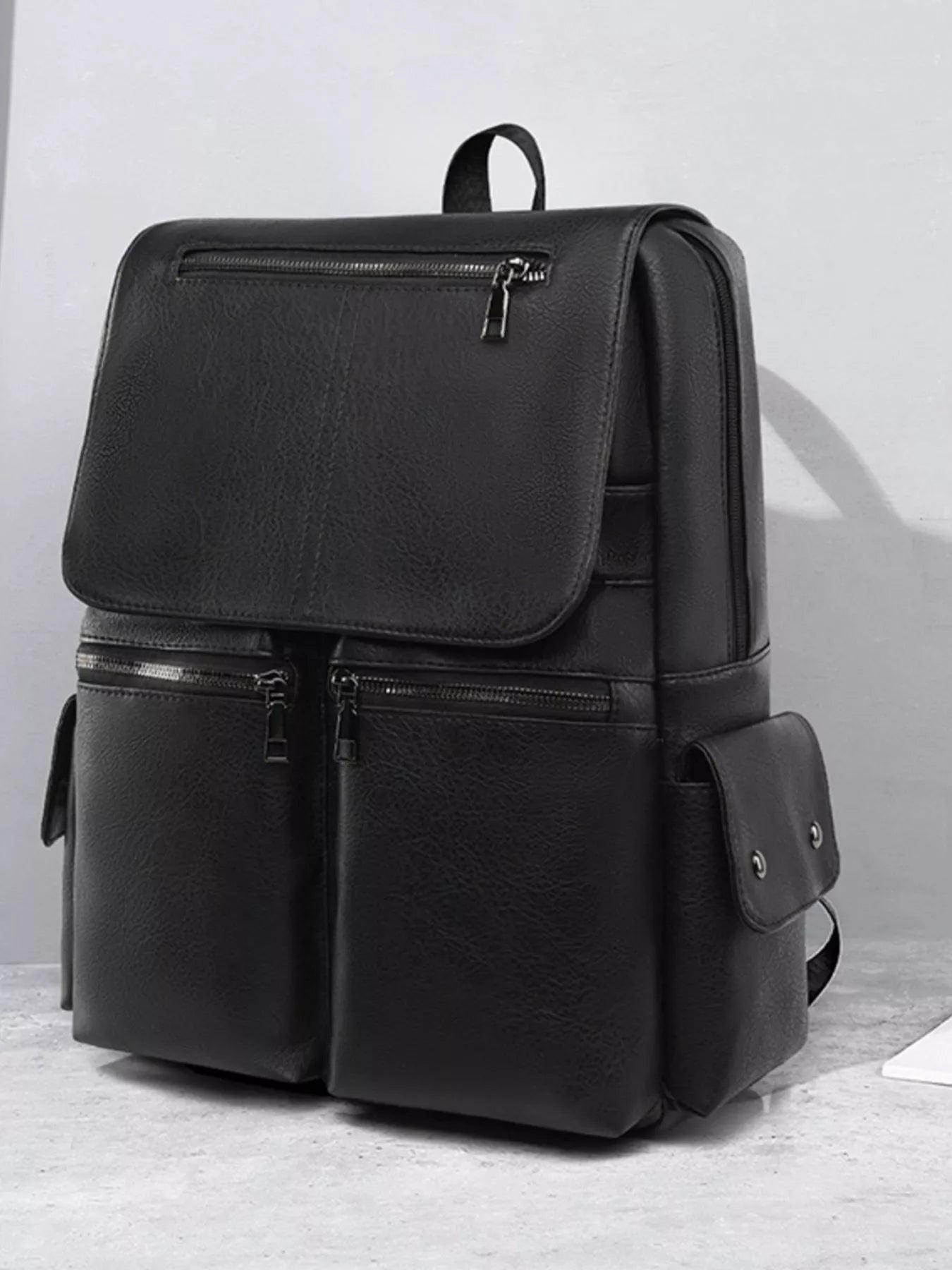 Black backpack on a light gray surface with a neutral background