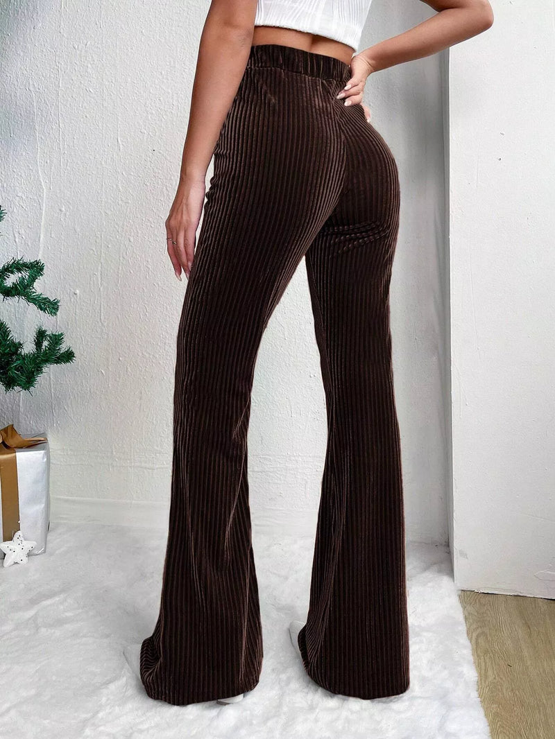 Brown corduroy flared pants worn by a person on a white background
