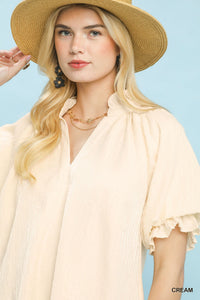 Woman wearing a cream blouse and straw hat against a light blue background