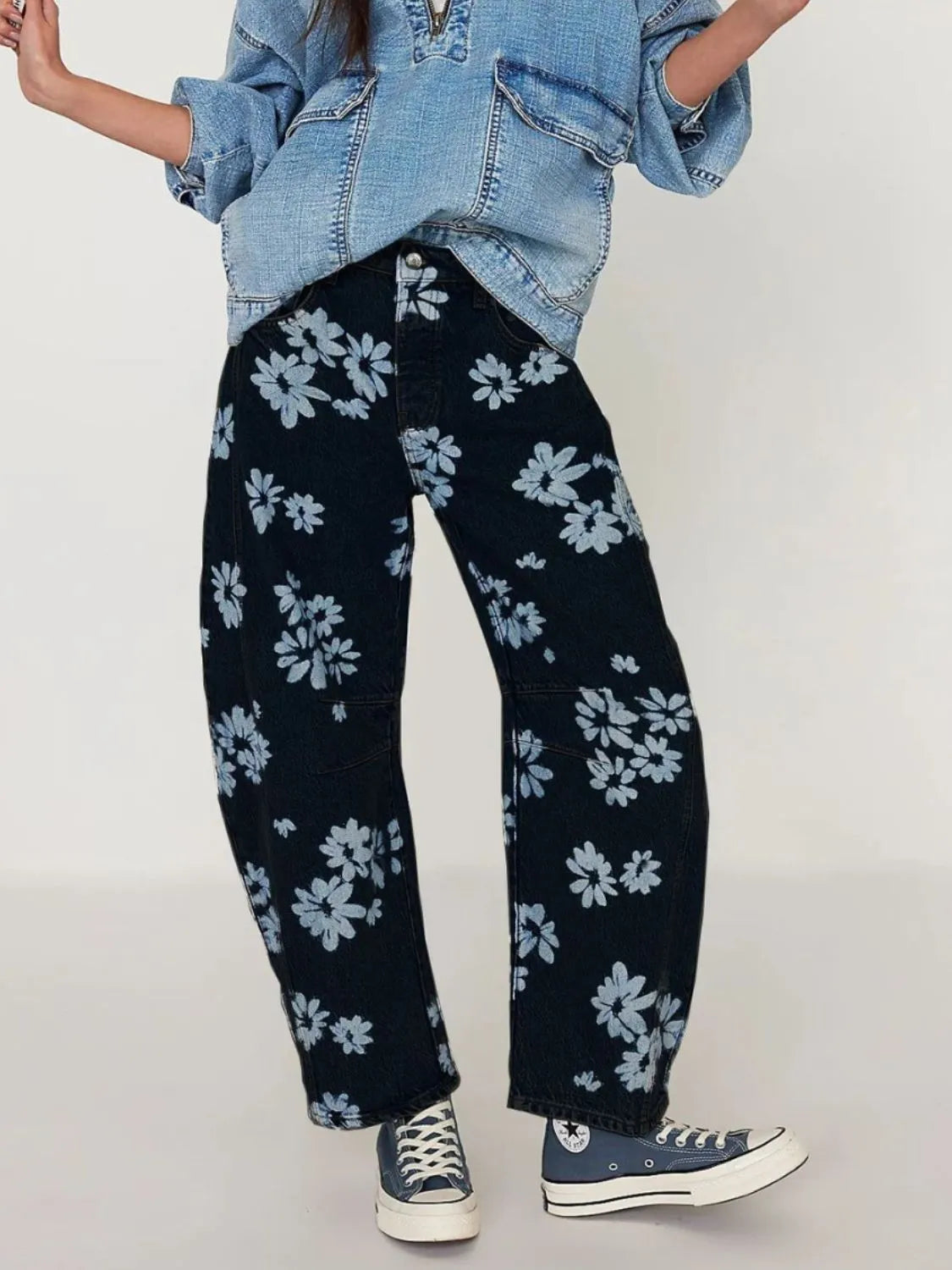 Person wearing navy floral pants with a light blue denim jacket on a plain background