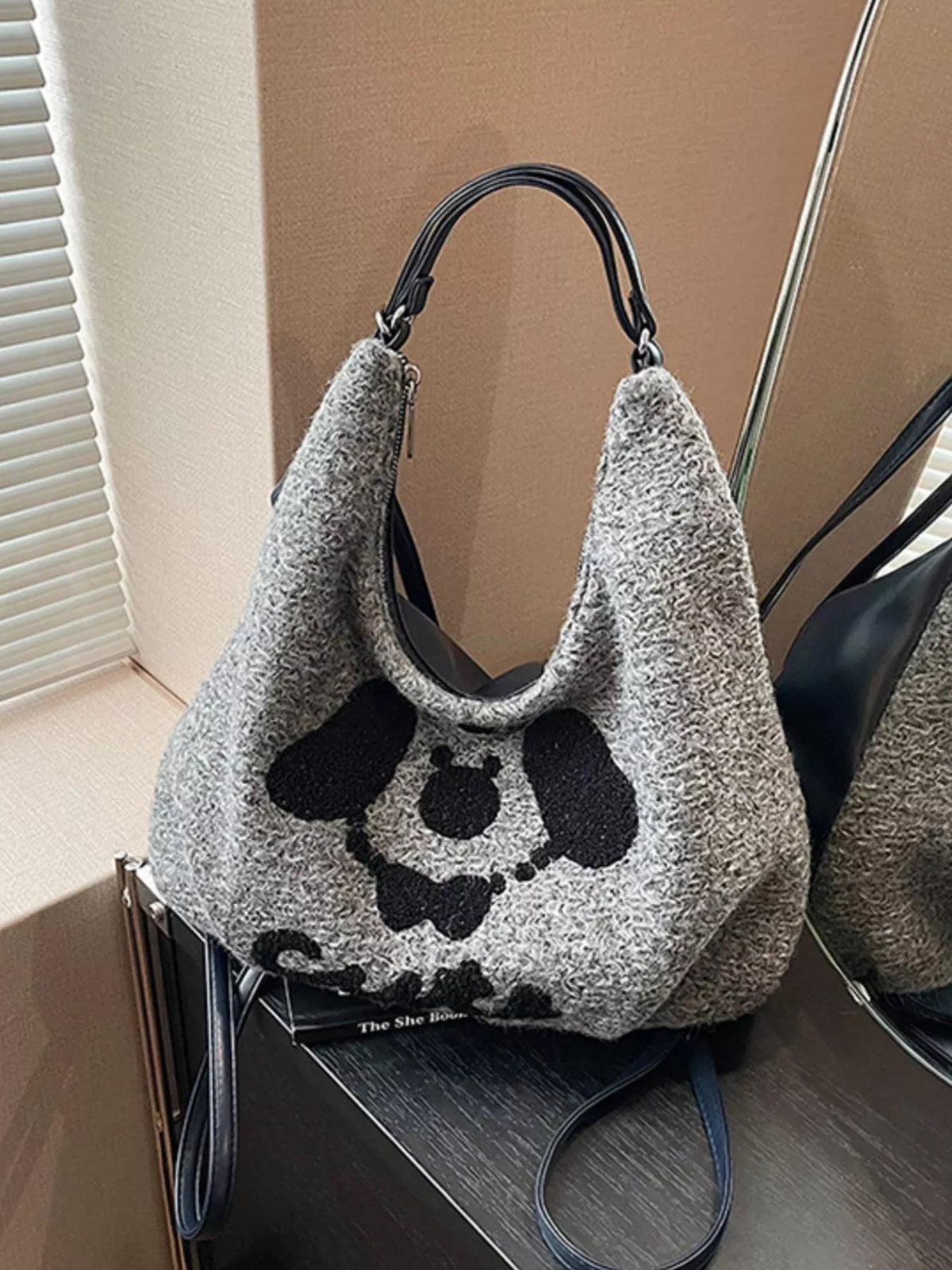 Textured handbag with black paw prints on a wooden surface