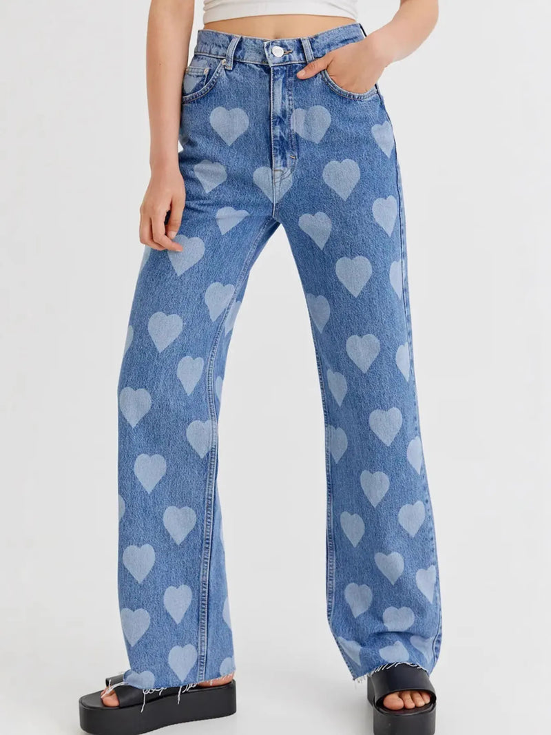 Blue jeans with heart patterns worn by a person on a white background