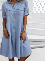 Woman wearing a light blue denim dress standing on steps.