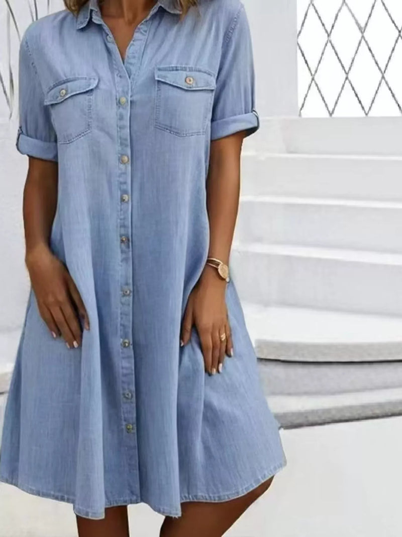 Woman wearing a light blue denim dress standing on steps.
