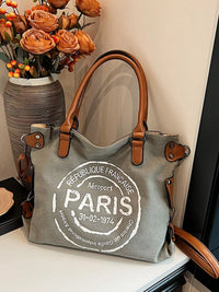 Gray tote bag with 'Paris' text on a surface with a vase of flowers in the background