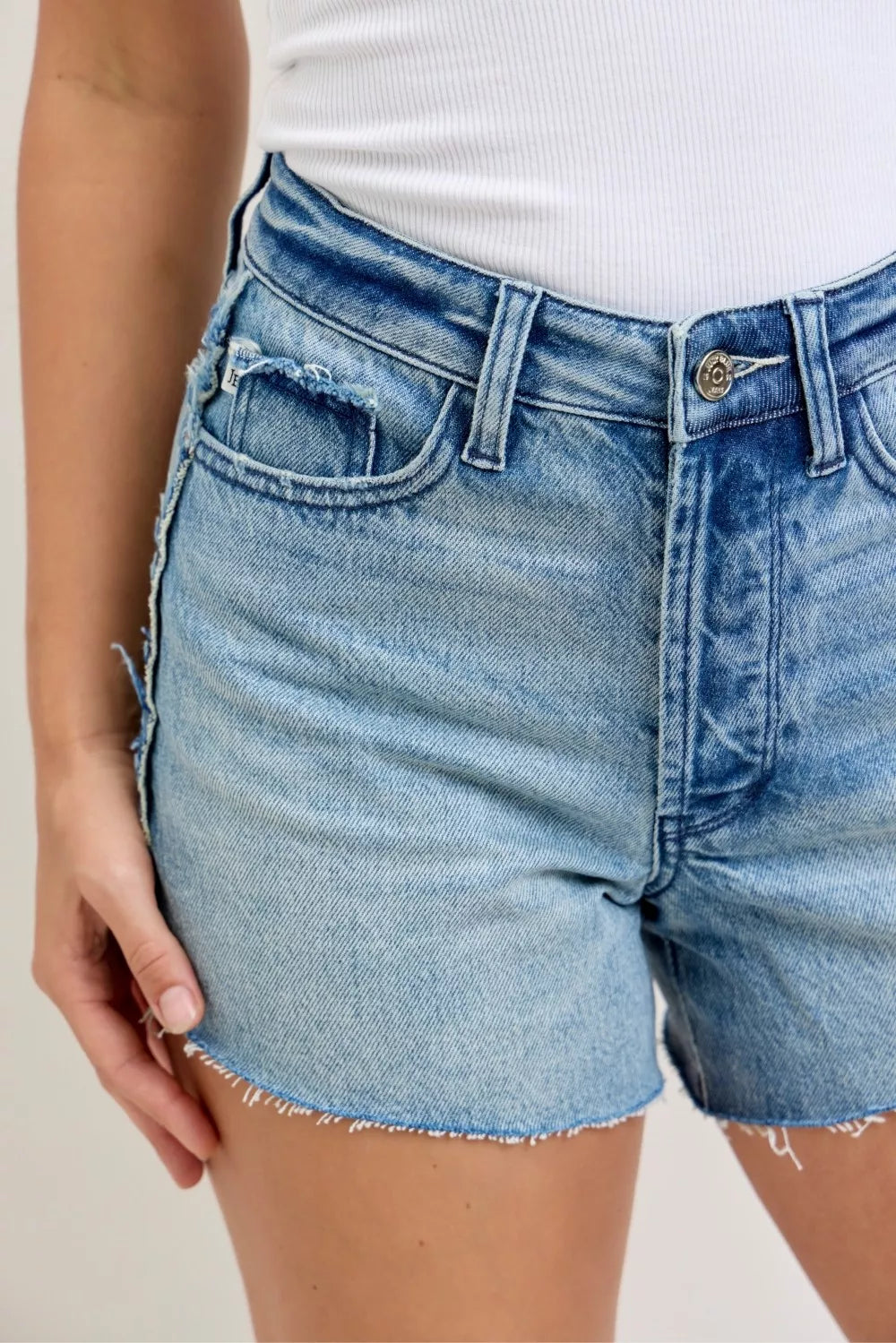 Blue denim shorts worn by a person on a neutral background