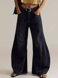 Person wearing wide-leg black jeans on a plain background
