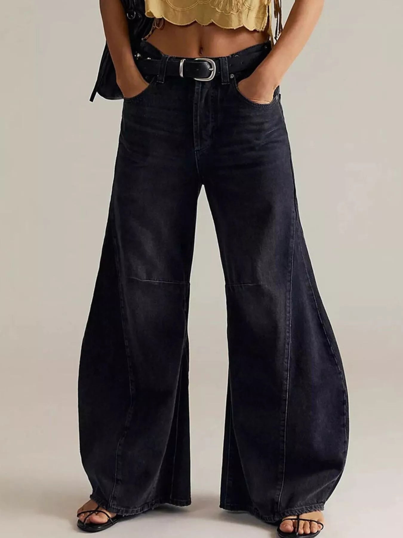 Person wearing wide-leg black jeans on a plain background
