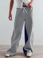 Person wearing striped pants and a white top on a plain background