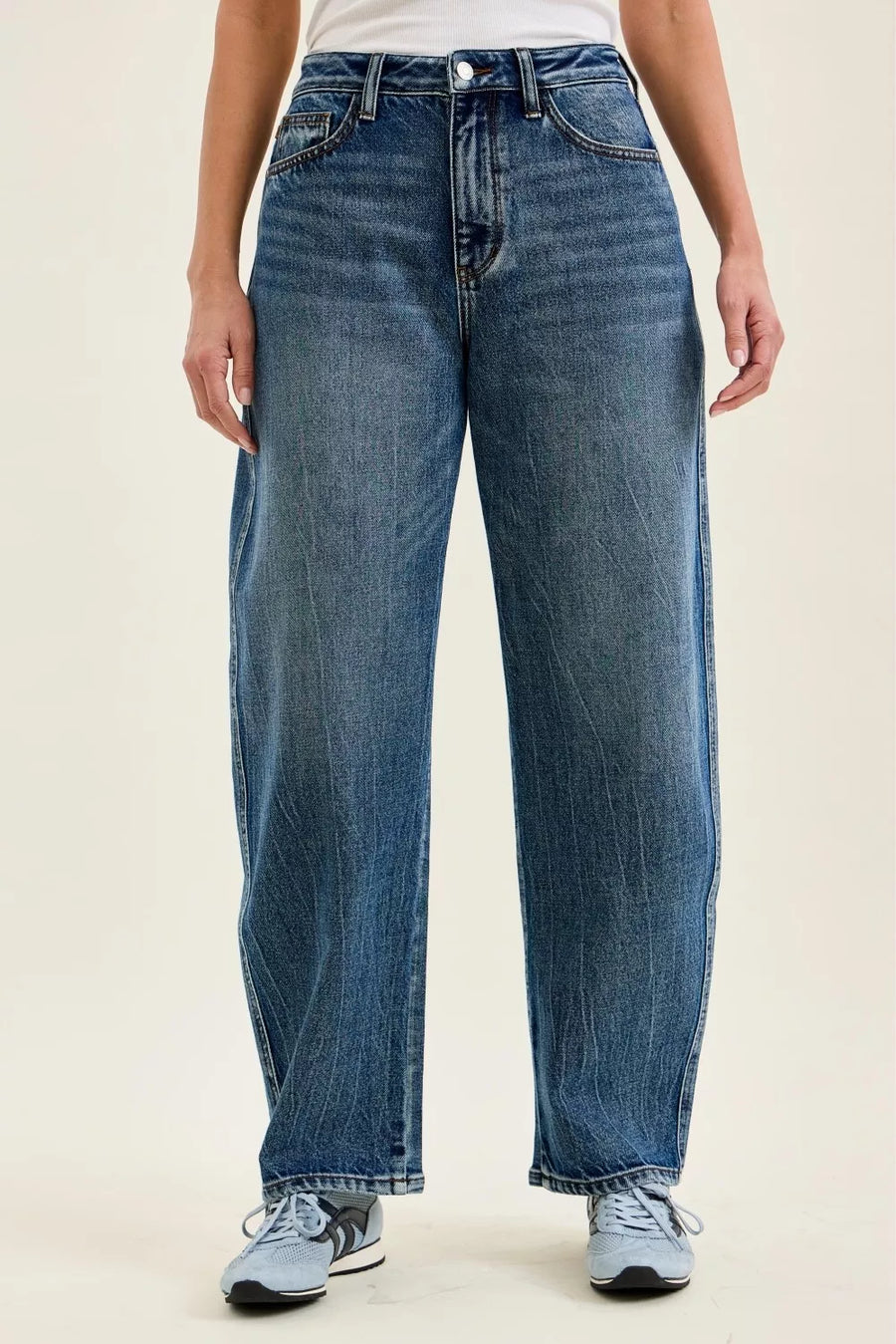 Person wearing blue jeans on a beige background