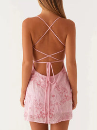 Pink lace dress with criss-cross back design on a white background