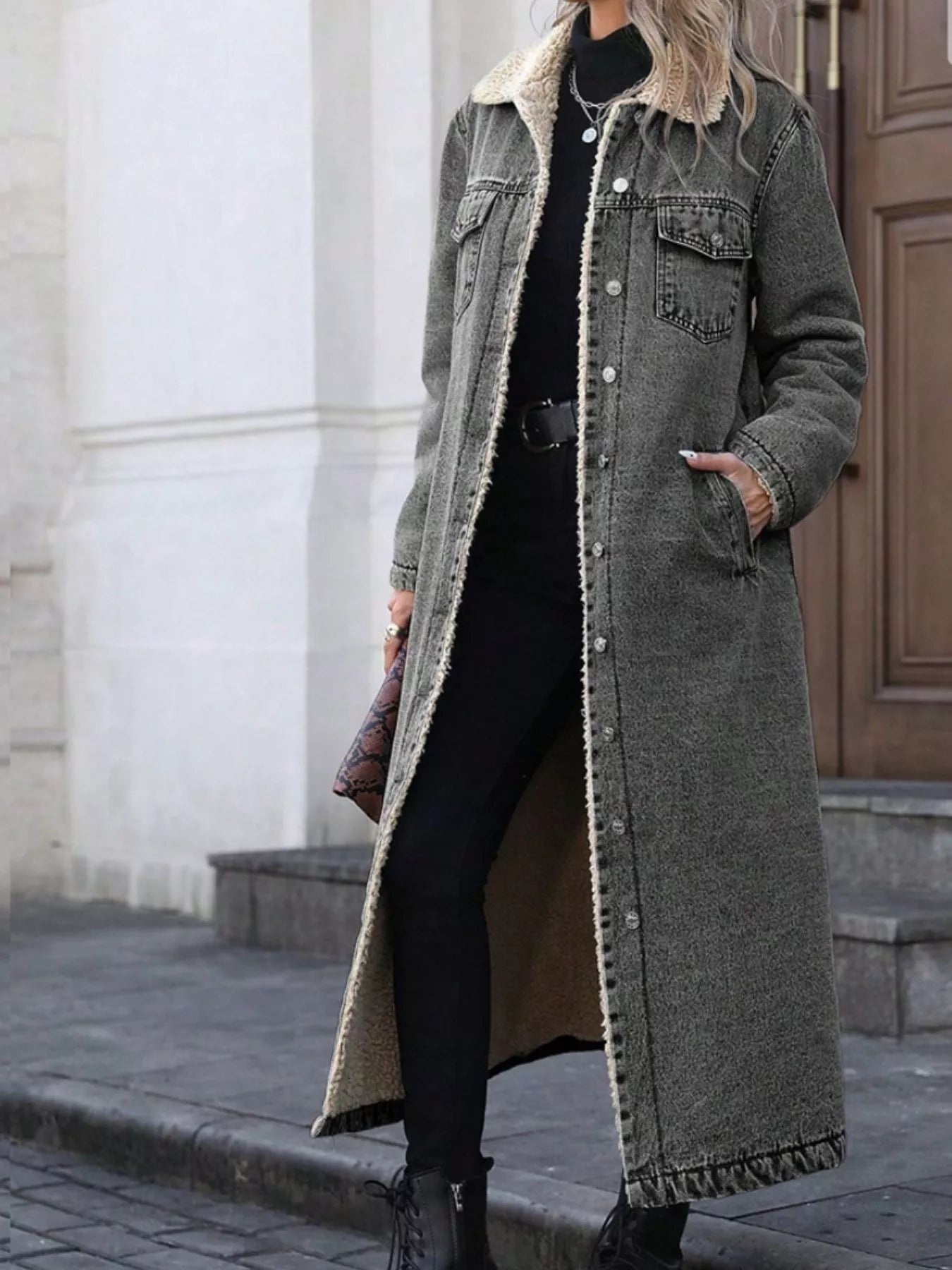 Person wearing a long gray coat with a fur-lined hood in an urban setting.