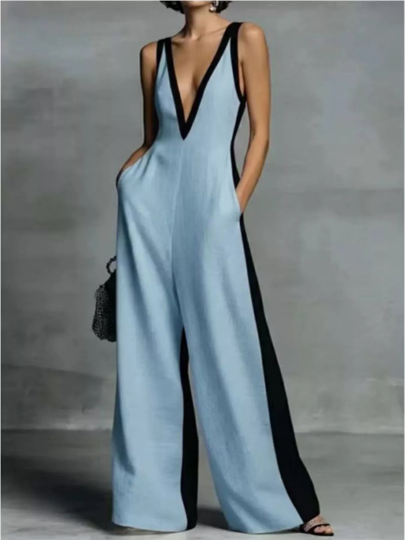 Woman wearing a light blue jumpsuit with black accents on a gray background