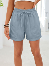 Person wearing light blue shorts with a white background