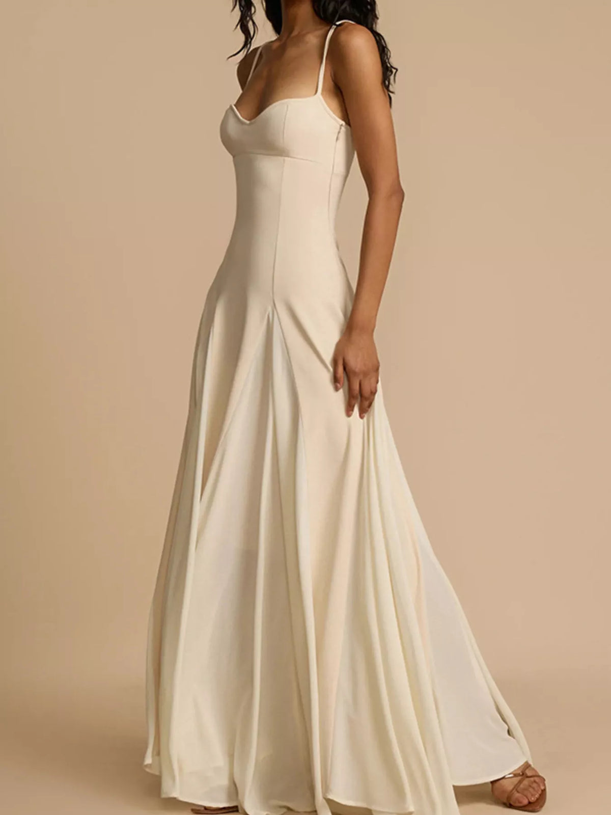 Woman wearing a long white dress against a beige background