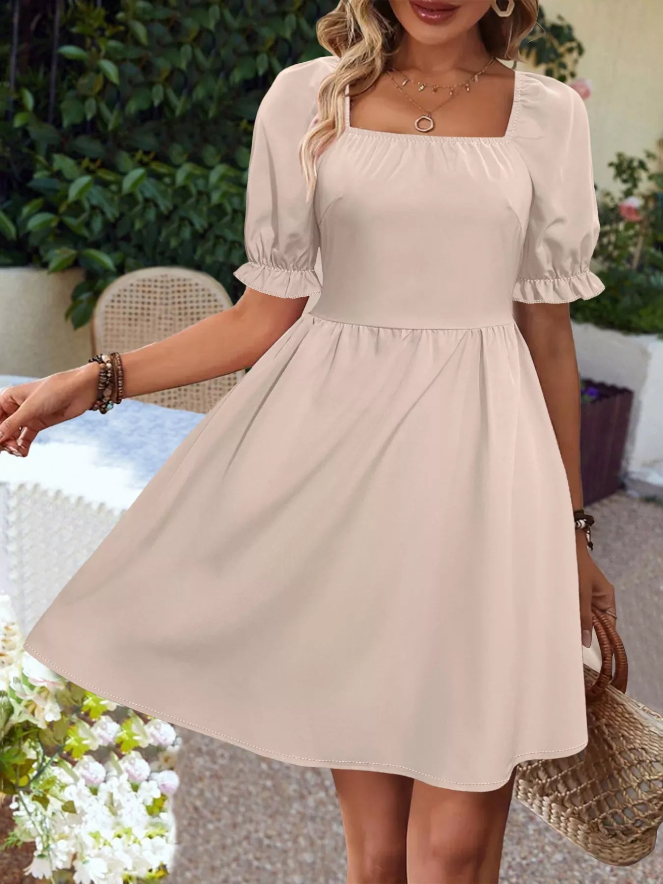 Woman wearing a beige dress with puff sleeves in an outdoor setting.