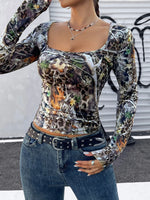 Person wearing a long-sleeve, multicolored patterned top with jeans in an urban setting.