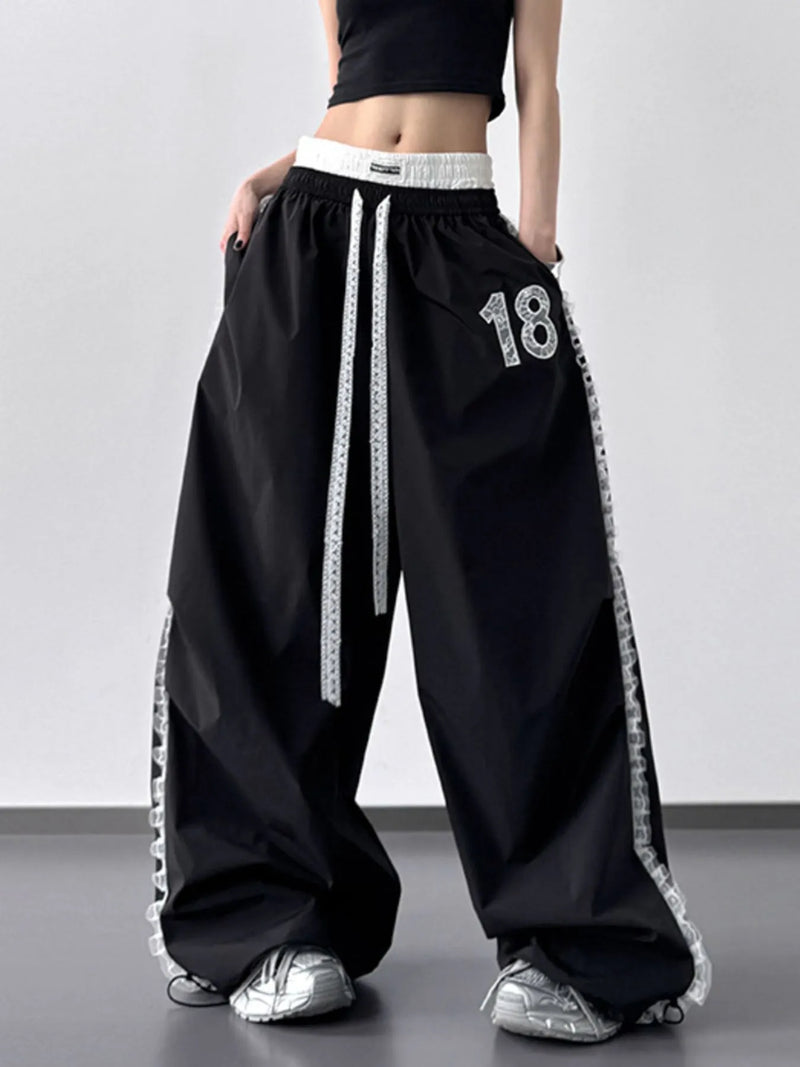 Black wide-leg pants with white trim and number 18, worn by a person on a plain background