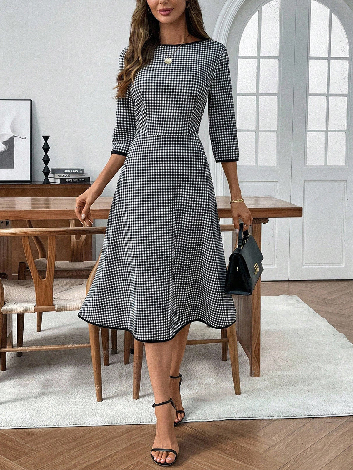 Woman wearing a black and white checkered dress in a modern room.