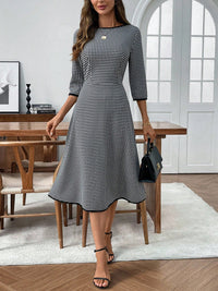 Woman wearing a black and white checkered dress in a modern room.