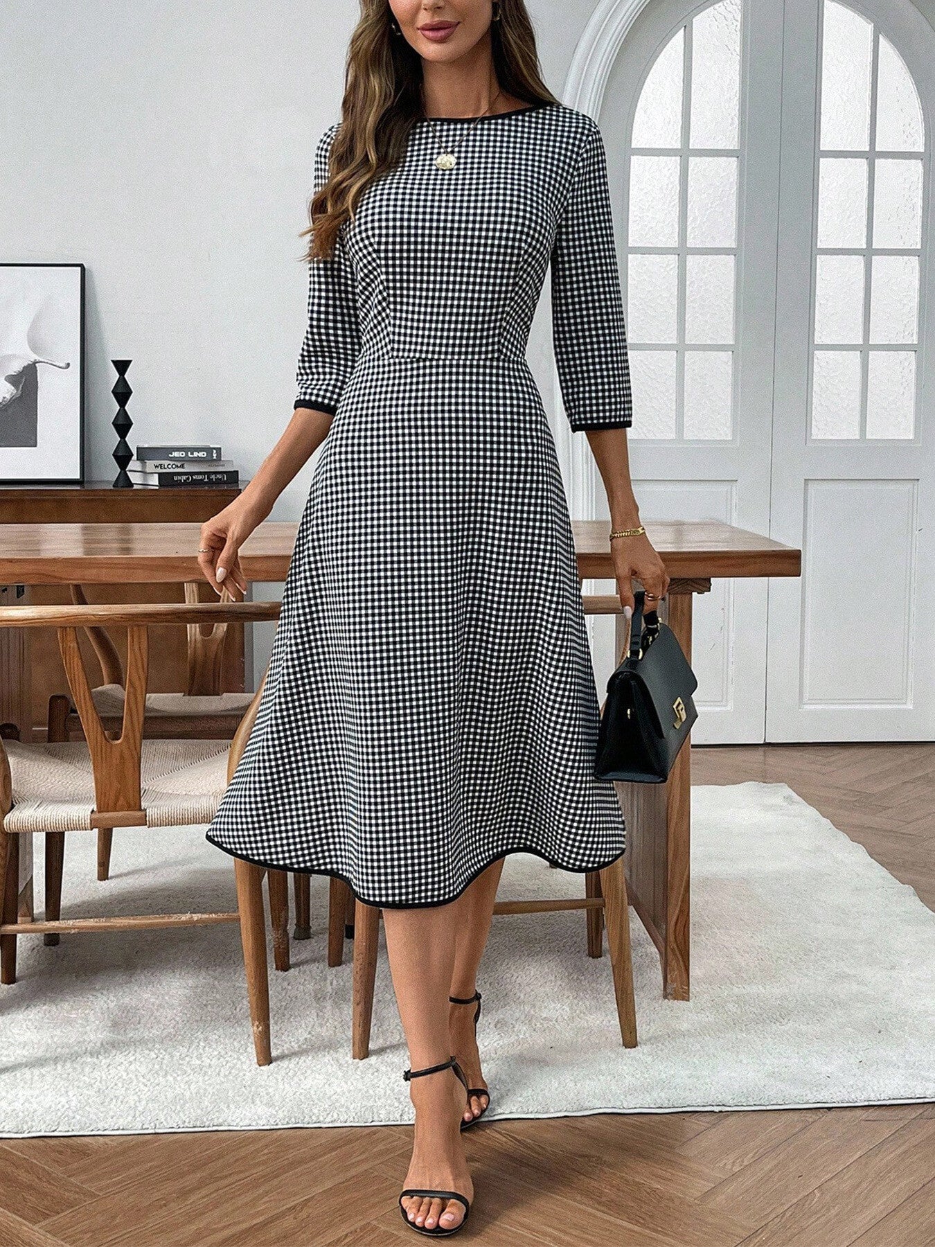 Woman wearing a black and white checkered dress in a modern room.