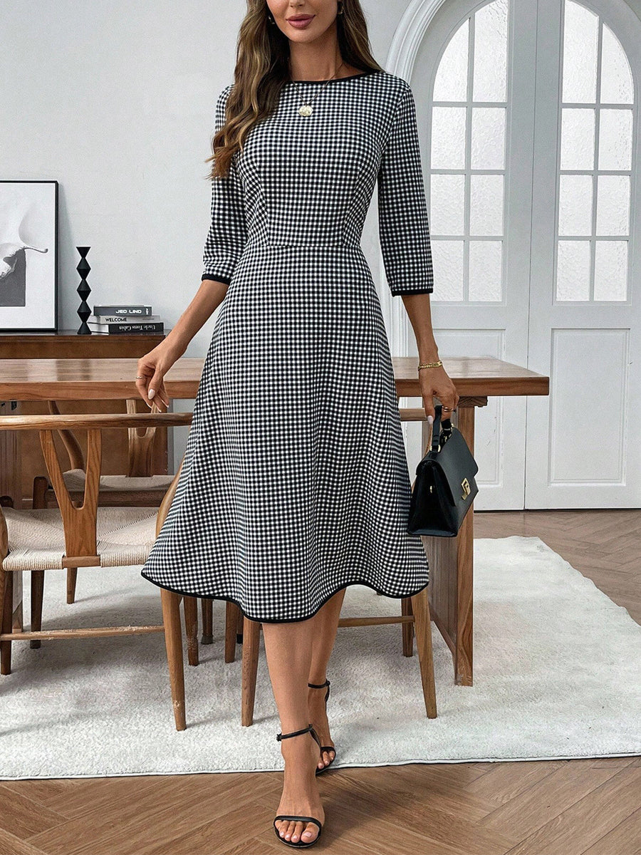 Woman wearing a black and white checkered dress in a modern room.