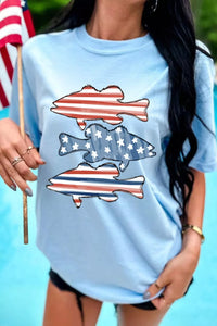 Woman wearing a light blue t-shirt with fish and American flag design, holding an American flag.