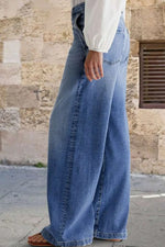 Person wearing wide-leg jeans with a stone wall background