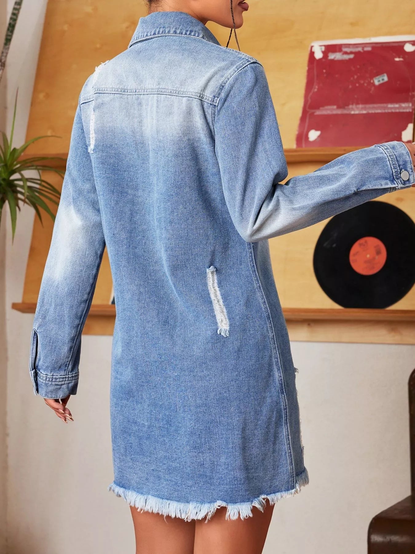 Person wearing a blue denim dress with a record player in the background