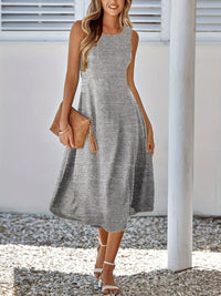 Woman wearing a gray sleeveless dress holding a brown clutch.
