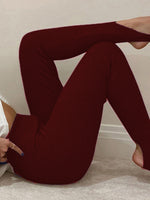 Person wearing burgundy ribbed leggings sitting on a light-colored floor.