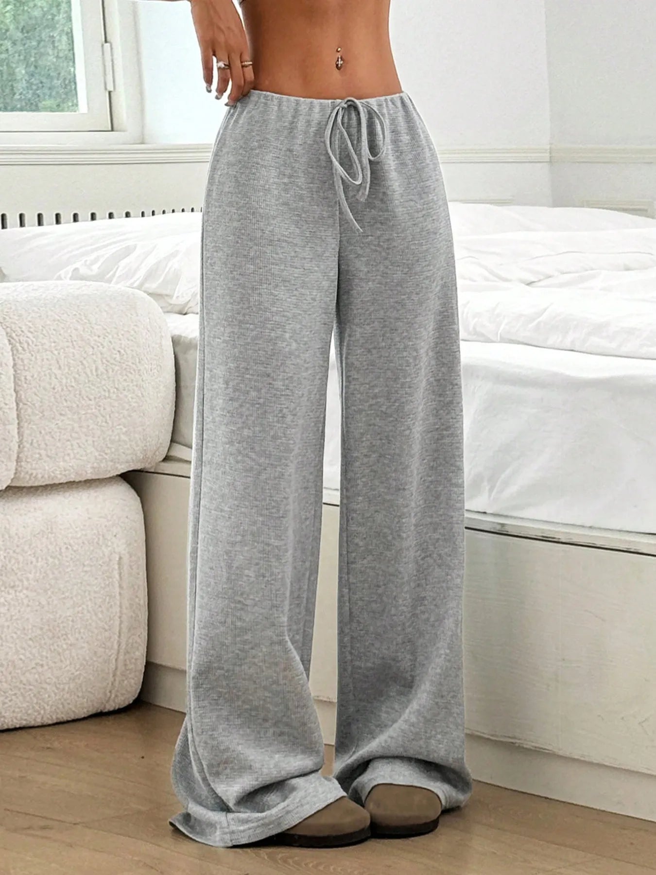 Person wearing gray sweatpants in a room with a bed and sofa.