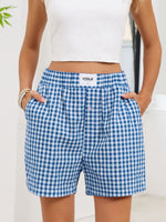 Person wearing blue gingham shorts with a visible 'Vogue' label, standing against a white background.