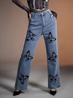 Blue jeans with black butterfly patterns worn by a person on a neutral background