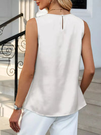 Person wearing a white sleeveless top and white pants outdoors.