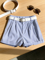 Blue striped shorts with a white belt on a wooden surface, accompanied by a white belt and sunglasses.