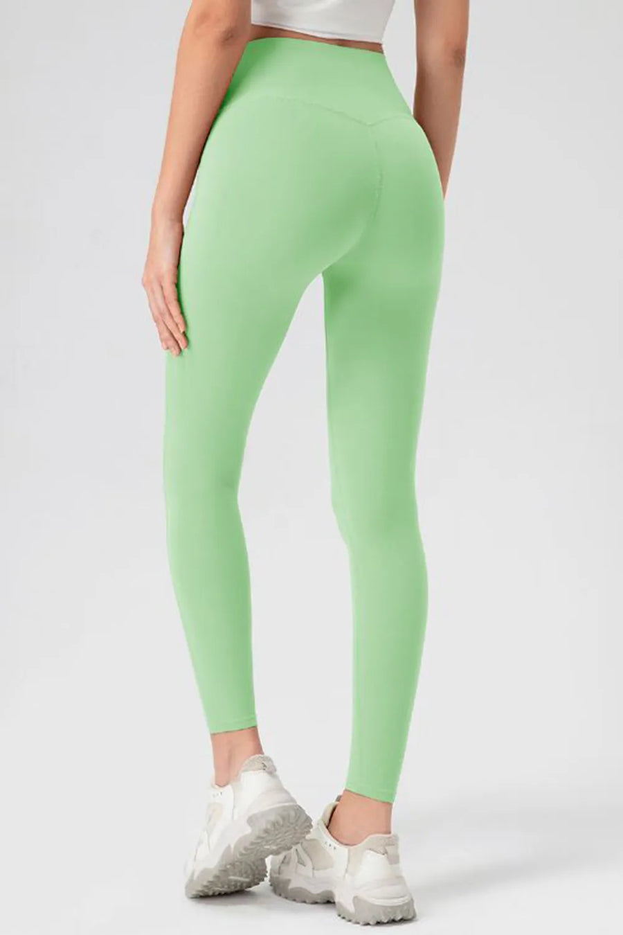 Person wearing light green leggings on a white background