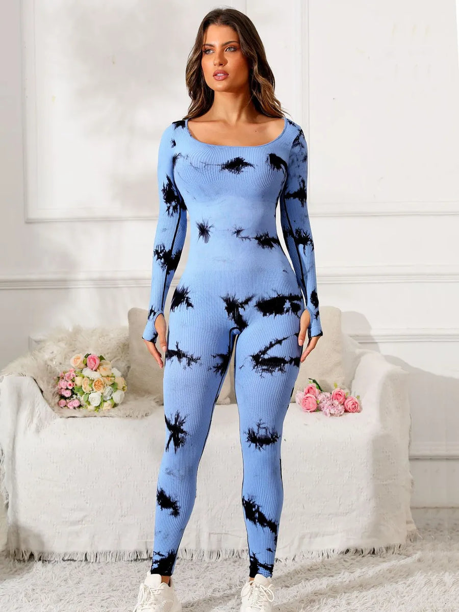 Woman wearing a blue and black tie-dye outfit in a room with white walls and a white couch.