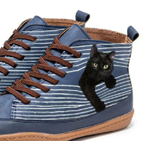 Blue striped sneakers with a black cat peeking out from inside on a white background