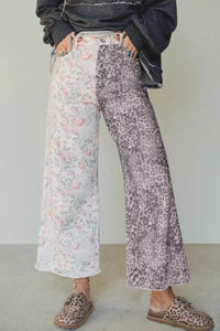 Person wearing a dark jacket, floral pants, and leopard print shoes on a plain background