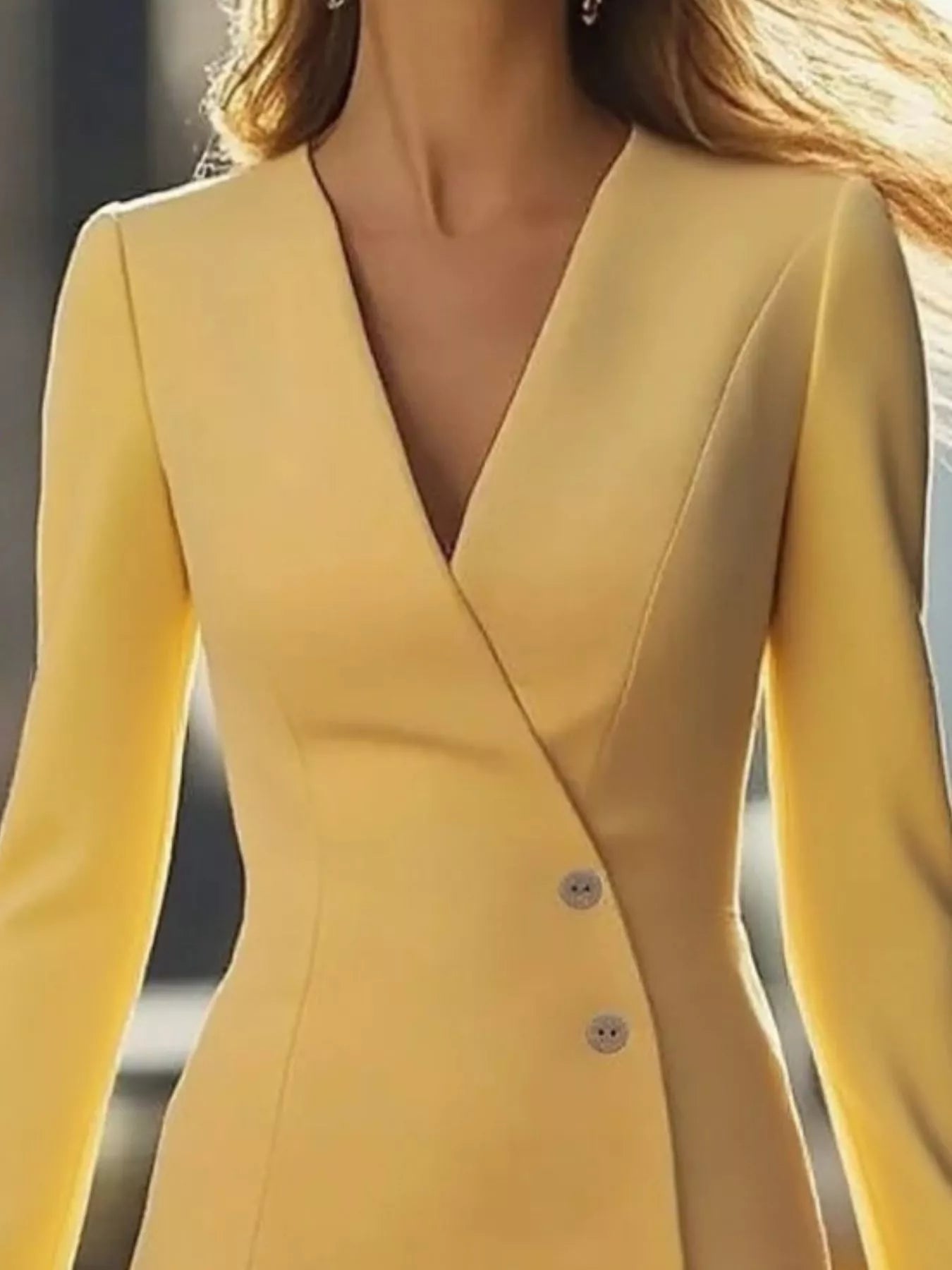 Yellow dress with a V-neck and buttons on a blurred background