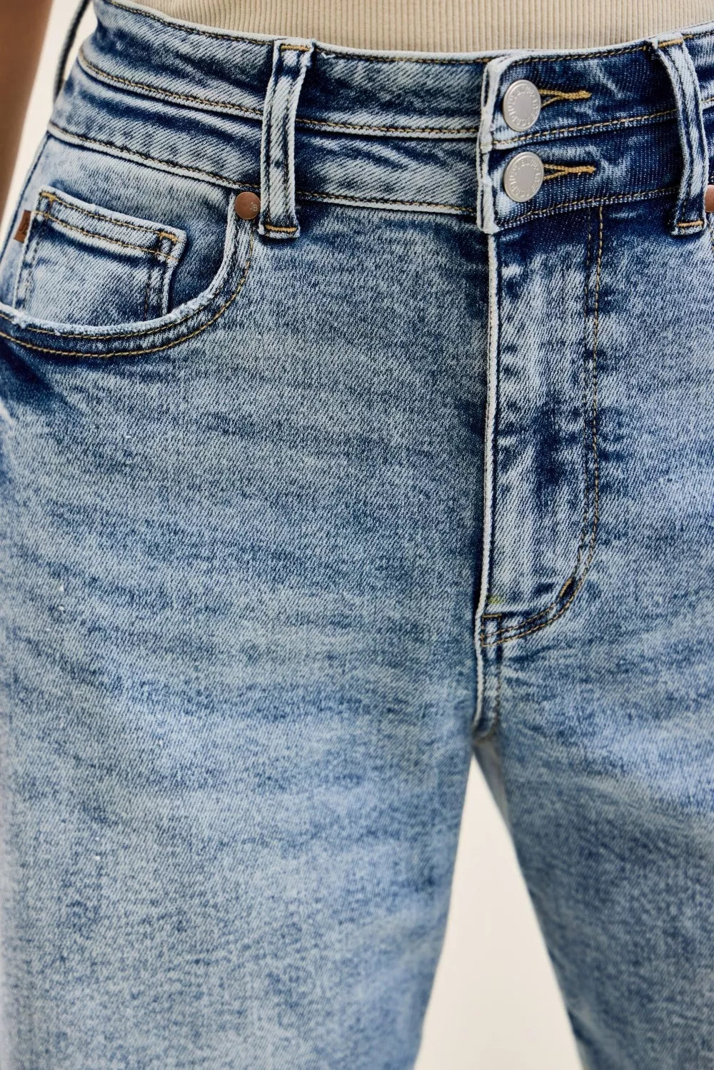 Close-up of blue jeans with a focus on the waistband and front pocket.