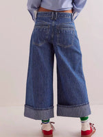 Wide-leg blue jeans worn by a person on a light background