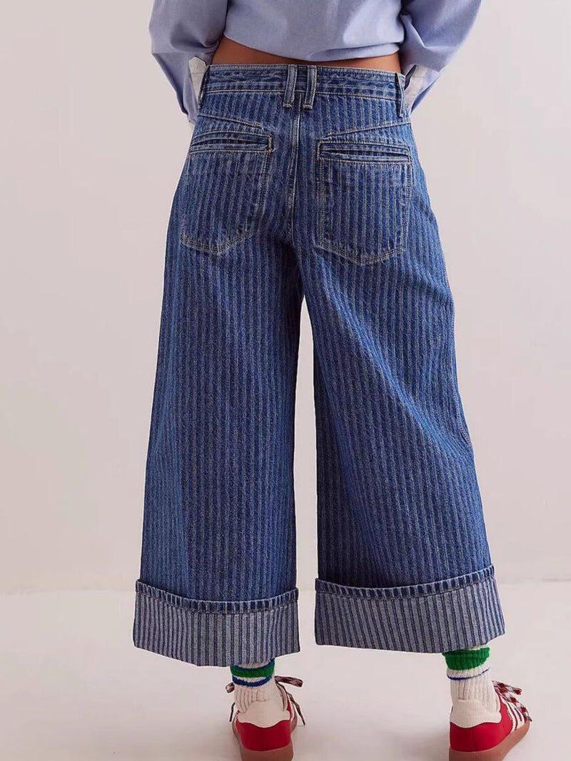 Wide-leg blue jeans worn by a person on a light background